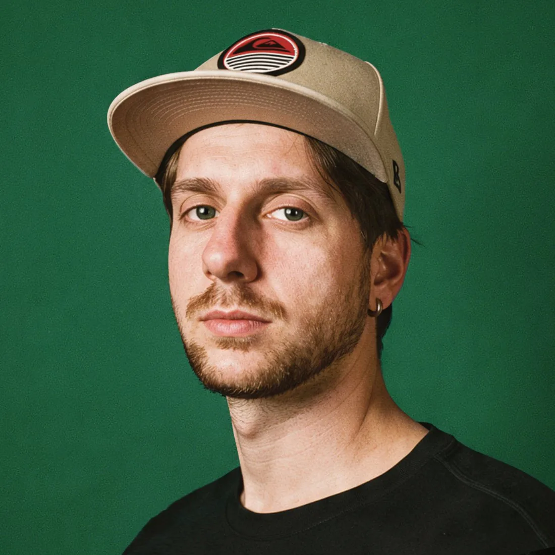 Julián Orlando, diseñador de marcas, con gorra sobre fondo verde